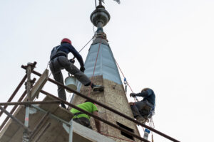 A church steeple under construction shows the importance of precision and safety in demanding church construction.
